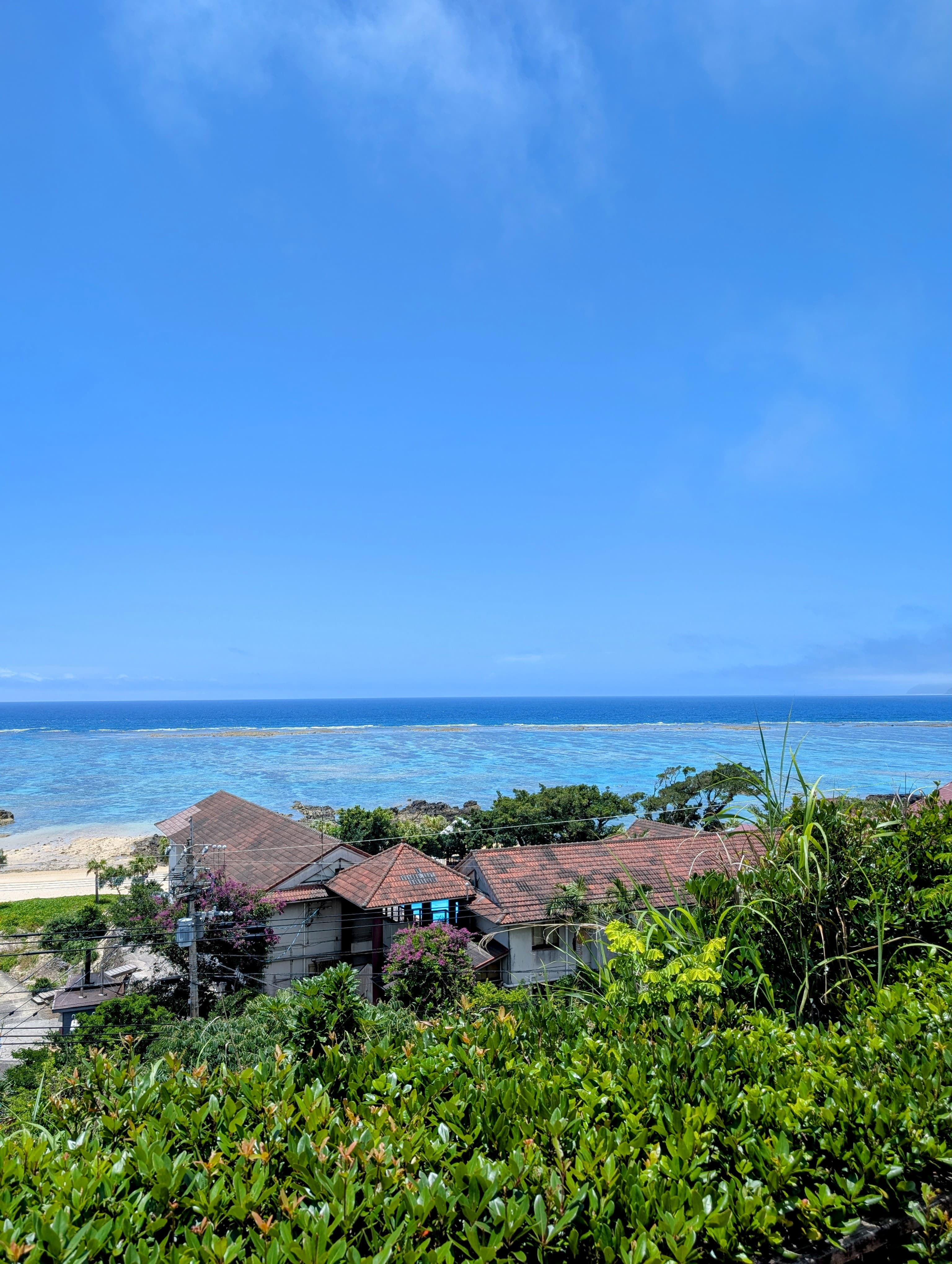 Coral-blue sea off a southern coast with a tiled-roof house