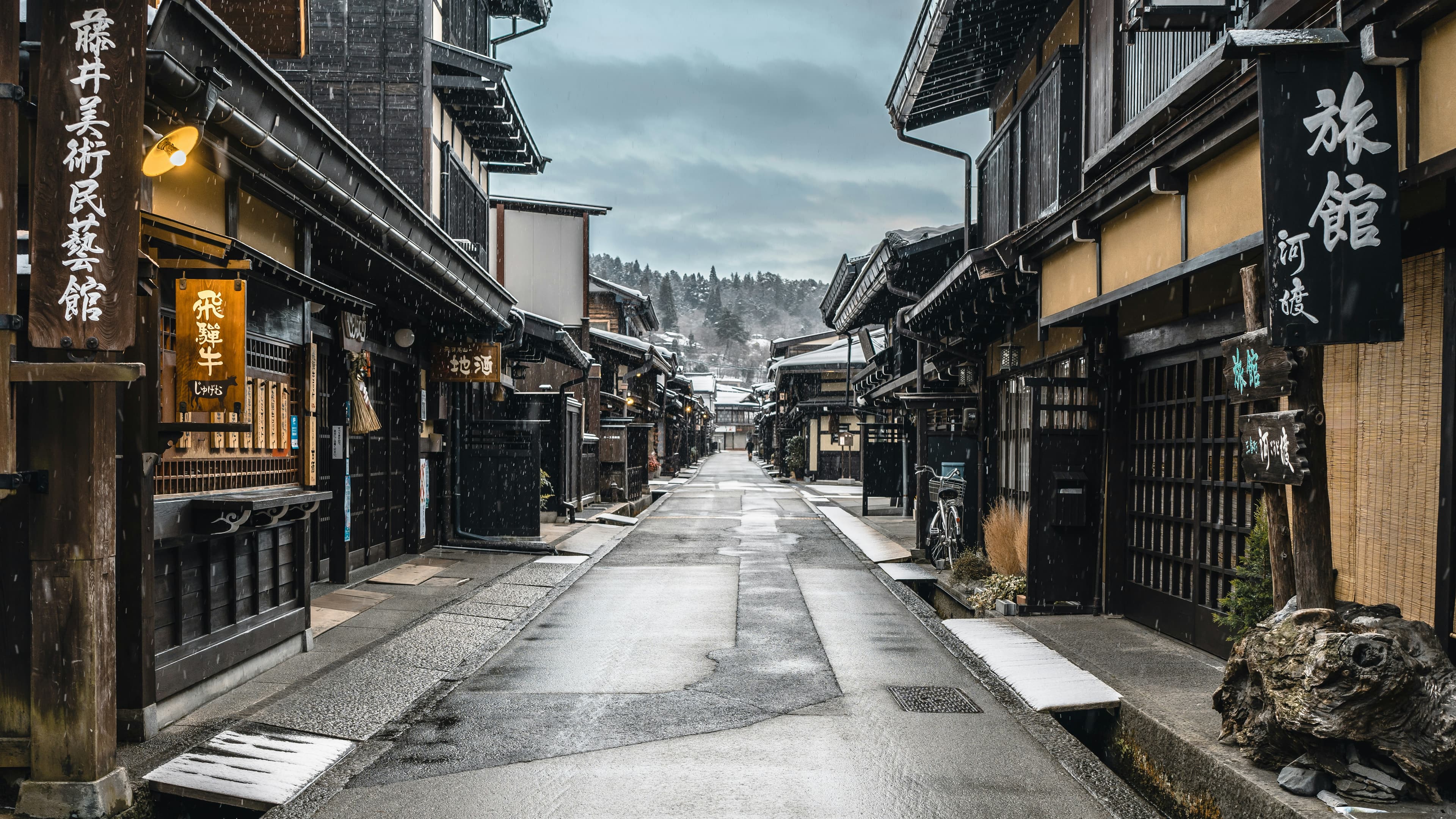 A historic wooden townscape street lined with traditional machiya and a ryokan